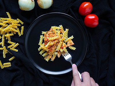 Fusilli 番茄酱鸡 配料西红柿 鸡肉 大蒜 胡椒 洋葱 是放在黑盘黑色织物背景上的意大利食物盘子美食面条猪肉蔬菜食谱黑布海图片