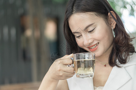 紧闭女人喝清晨玻璃茶和灯光的茶图片