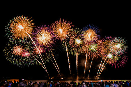 欢呼的人群在节日期间观看五颜六色的烟花并在海滩上庆祝幸福焰火天空火箭娱乐干杯舞蹈新年庆典夜生活图片