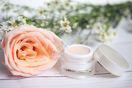 护肤概念 粉红色护肤补救霜产品 包装中带有空白标签 背景为大粉红玫瑰和小白花图片