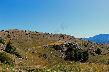 山丘 喀斯特山峰 草地 树木和远处的山峰 Bjelasnica山图片