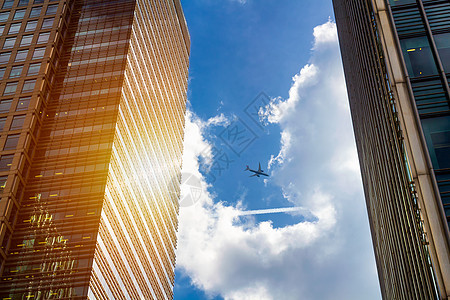 具有商业办公室塔背景的空中飞机休光灯框架天空建筑城市太阳金融空气景观喷射建筑学图片