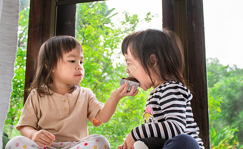 亚洲小女孩和妹妹 正在房间里吃香蕉蛋糕 很好吃 笑声  谢谢快乐孩子们香蕉巧克力蛋糕食物童年女孩女性面包图片