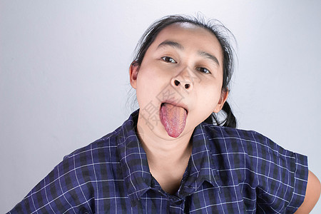身穿蓝色衬衫的亚洲年轻女性 做鬼脸 长舌头 让你快乐而不压力 肢体语言和鼓励概念图片
