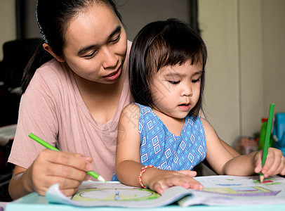 亚裔母亲在放学后帮助女儿做功课 家庭教学概念图片