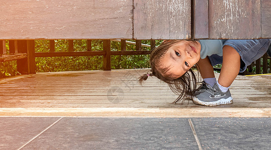 快乐的亚洲小女孩 在花园的木门下面玩偷猎游戏 (笑声)图片