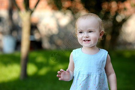 穿着蓝裙子的可爱小孩女孩孩子喜悦场地女儿金发女郎太阳生活草地蓝色微笑图片