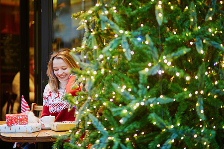 女孩在节日毛衣 喝咖啡或热巧克力 在咖啡馆装饰圣诞节盒子季节咖啡金发惊喜女士咖啡店礼物快乐庆典图片