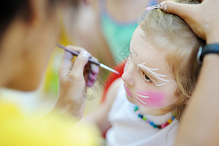 可爱的姑娘被画上脸色喜悦幼儿园化妆品画家绘画舞会孩子创造力快乐微笑图片