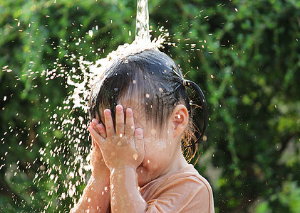可爱的亚洲小女孩玩得开心 在夏令营里玩水喷水管晴天软管乐趣家庭后院女孩童年洒水器公园微笑图片