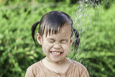 可爱的亚洲小女孩玩得开心 在夏令营里玩水喷水管孩子们花园家庭浴缸微笑软管公园童年乐趣飞溅图片