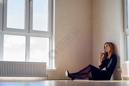 悲伤的女童坐在一个空空房间的地板上 里面装着大玻璃窗图片