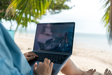 妇女使用笔记本电脑和智能手机在海滩背景的度假卡迪学习药片商业女士展示技术电话场所工作社会专注图片