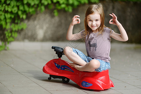 可爱的小女孩驾驶玩具车幸福司机操场幼儿园车辆女儿女孩喜悦闲暇童年图片