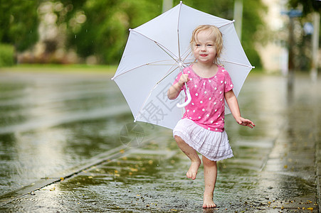 可爱的小小孩女孩 在雨下玩得开心水滴微笑飞溅金发女郎城市水坑赤脚快乐乐趣闲暇图片