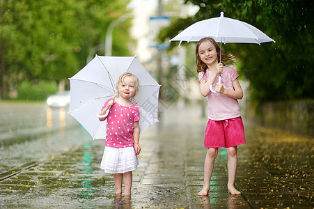 两个可爱的小妹妹 在雨下玩得开心飞溅舞蹈水滴城市快乐闲暇水坑乐趣女孩兄弟图片