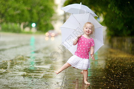 可爱的小小孩女孩 在雨下玩得开心舞蹈女性赤脚女孩孩子城市享受闲暇金发女郎乐趣图片