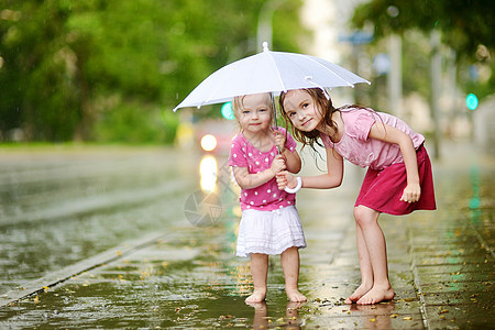 两个可爱的小妹妹 在雨下玩得开心女性舞蹈快乐城市街道水滴自由水坑闲暇兄弟图片