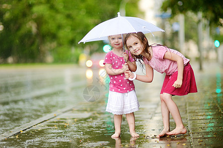 两个可爱的小妹妹 在雨下玩得开心城市舞蹈快乐孩子水坑水滴乐趣飞溅自由女孩图片