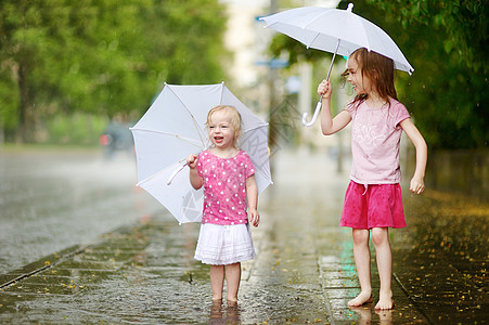 两个可爱的小妹妹 在雨下玩得开心孩子女性人行道赤脚兄弟乐趣城市朋友们街道自由图片