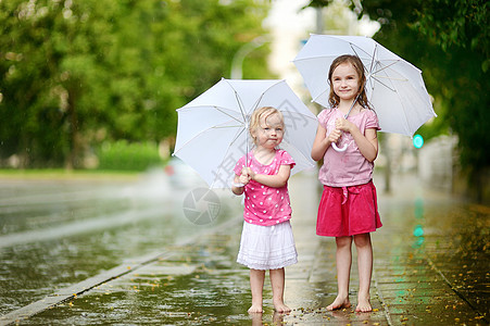 两个可爱的小妹妹 在雨下玩得开心女孩团队兄弟城市水滴印象赤脚飞溅闲暇姐姐图片