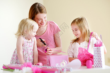 母亲和两个女儿在包着礼物展示生日假期圣诞礼物女性惊喜女士女孩纪念日朋友图片