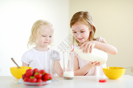 两个姐妹吃麦片加牛奶孩子早餐桌子微笑女性玉米朋友们姐姐水果兄弟图片