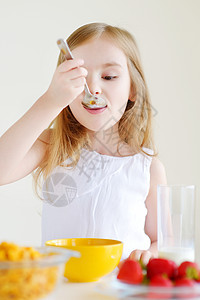 小女孩用牛奶吃麦片谷物食物玉米勺子水果午餐桌子玻璃微笑快乐图片