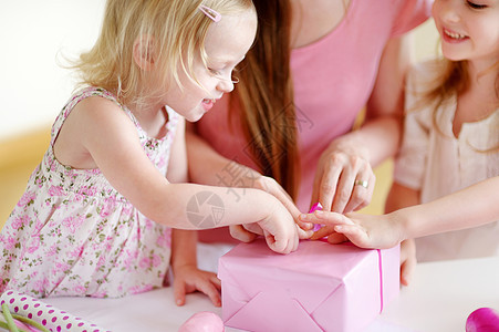 母亲和两个女儿在包着礼物喜悦丝带包装孩子愿望姐姐圣诞礼物纪念日假期展示图片