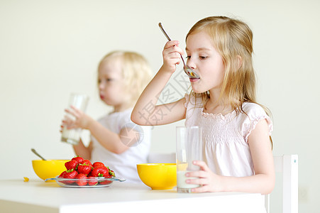 两个姐妹吃麦片加牛奶饮食幸福孩子乐趣童年姐姐食物小吃薄片桌子图片
