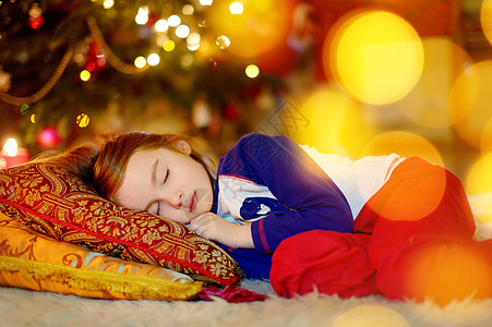 女孩睡在圣诞树下面的小女孩童年地面睡衣椅子礼物睡眠季节回忆蜡烛愿望图片