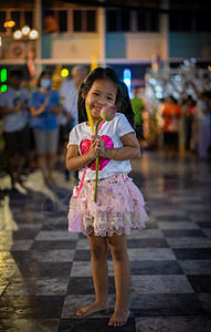 小女孩拿着蜡烛和莲花 为佛教祭坛鼓掌图片
