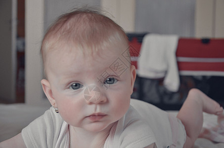 6个月大的迷人蓝眼女婴爬在床上 身穿体服的女婴图片