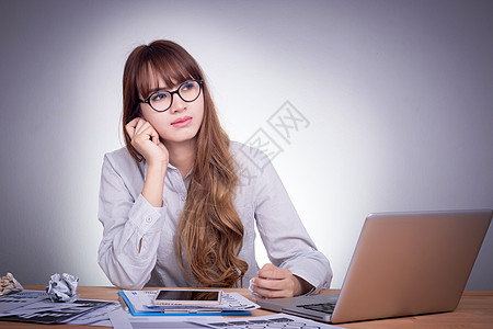 在一个现代办公桌的亚洲年轻办公室女青年 从事笔记本电脑工作 不集中工作 感到无聊图片