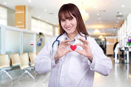 持有红心的年轻亚洲女医生 站在医院背景上 健康护理概念 医疗图片