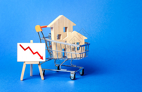 购物车中的木屋和带红色向下箭头的画架 房地产市场下跌 便宜的租金 需求减少 经济衰退 销量低 价值成本下降 流动性吸引力差图片