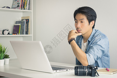亚洲摄影师或自由侠在La前认真思考的企业家笔记本休闲上班族员工工人工作办公室男性技术图片