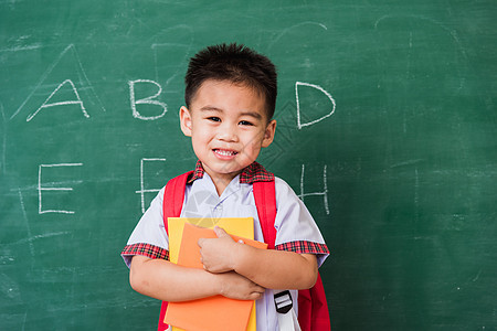 身着校服 有书包和Bob学生制服的幼童幼儿园手势拇指快乐课堂童年木板瞳孔黑板男生微笑图片