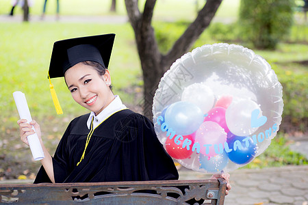 穿着学术服和学校服装的年轻快乐女毕业生肖像仪式女孩证书教育女性长袍大学微笑成人成功图片