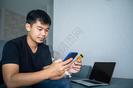 亚洲人拿着信用卡 在家里使用智能手机网上购物 网上购物 电子商务 网上银行 花钱 在家工作图片