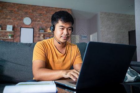 亚洲商务人士正在使用笔记本电脑 并穿戴耳机在网上开会和在家工作时使用耳机服务成人技术网络视频互联网男性娱乐学习商业图片