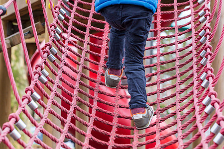 绳索攀爬框架上的小男孩低角度男生网络仪器孩子装备操场登山设备梯子图片