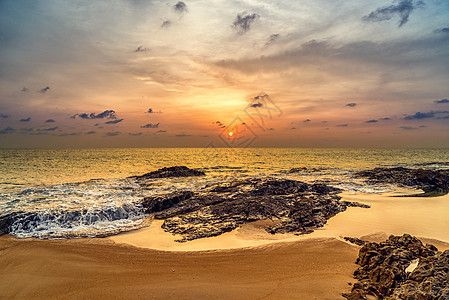 高湖沙滩上日落波浪橙子泡沫地平线天空反射巨石海洋支撑海滩图片