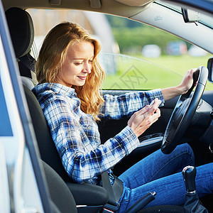 妇女驾驶汽车时使用智能手机旅行专注镜子安全成人网络车轮车辆电话学习图片