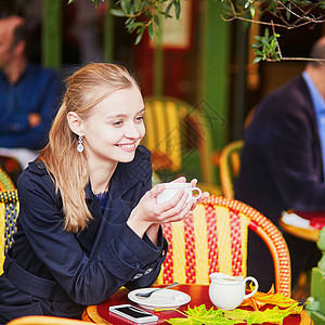 美丽的年轻女子在巴黎户外咖啡厅喝热巧克力照片杯子餐厅潮人女孩乐趣可可女士玻璃电话图片