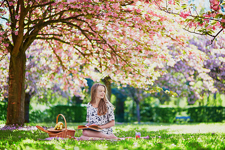 女孩在樱桃花园野餐和阅读书图片