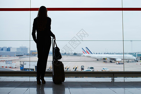 国际机场提着手提行李的女人 透过窗户看飞机女孩航班旅行旅游套装人员游客商业全体假期图片