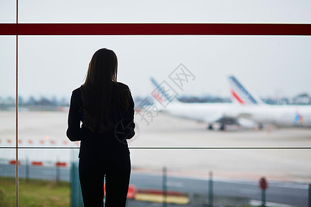 国际机场提着手提行李的女人 透过窗户看飞机服务员手提箱航空公司人员套装航班运输玻璃旅游滑板车图片