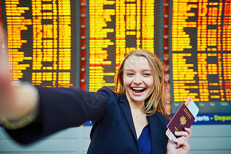 年轻旅行者在国际机场做自相自拍手提箱手机护照女士自拍航班行李女孩套装成人图片