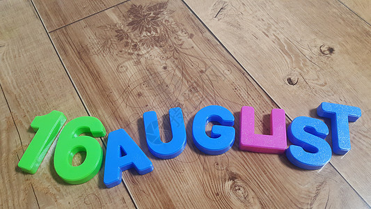 8月16日被放在木制地板上 用可塑彩色字母拼写成单词图片